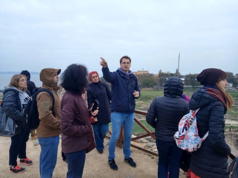 Историк показывает направление с крепостной площадки, на фоне лимана и города